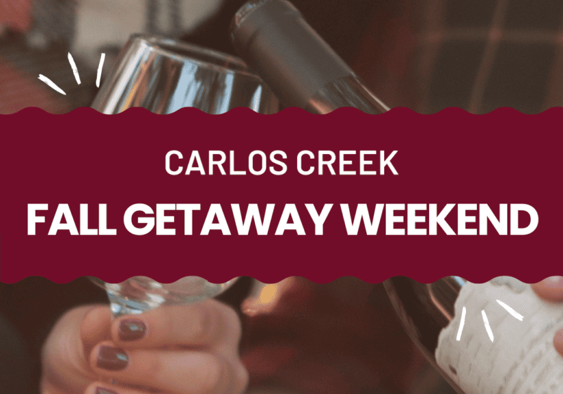 Two people clink wine glasses while pouring wine, both wearing plaid shirts. Text reads: “Carlos Creek Fall Getaway Weekend.” The scene captures a festive, cozy atmosphere—perfect for your ultimate Fall Getaway.