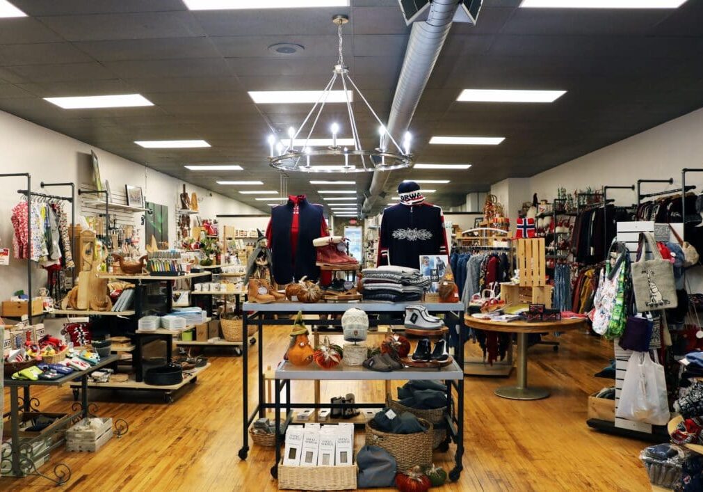 A boutique shop interior with wooden floors, display tables of clothes and accessories, and colorful racks—perfect for discovering new finds during spring in Alexandria or while exploring things to do in Alexandria.