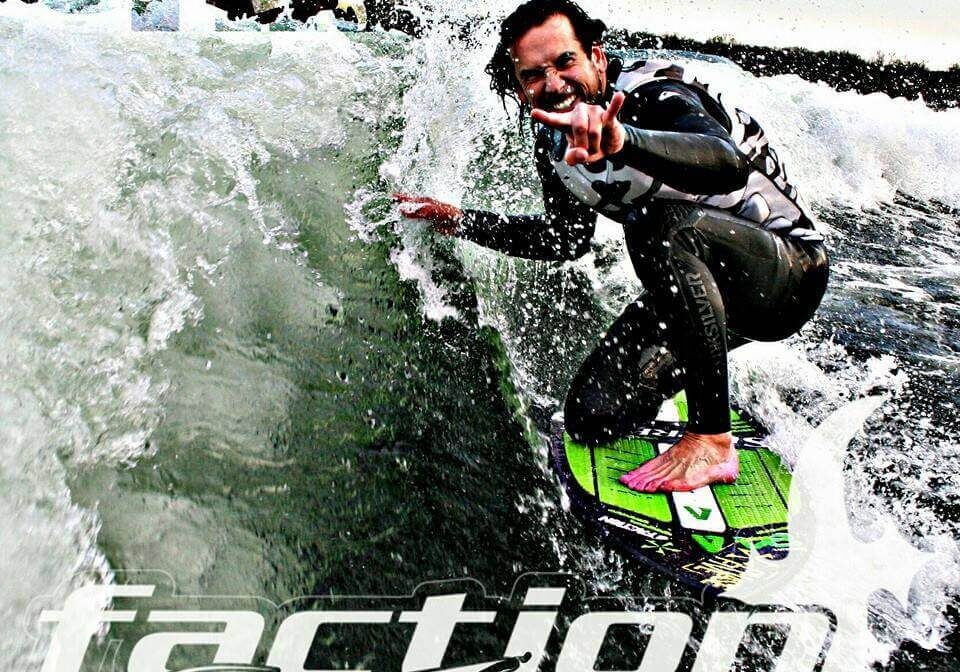 A man in a wetsuit surfs on a green board, smiling and flashing a peace sign as waves crash beside him. The text reads "Faction Marine, Alexandria, MN.