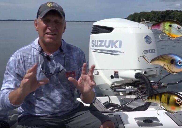 A man sits on a boat in front of a Suzuki 300 outboard motor, gesturing with his hands. Three colorful fishing lures are digitally added to the right side of the image, appearing to float in the air, highlighting his passion for fishing.